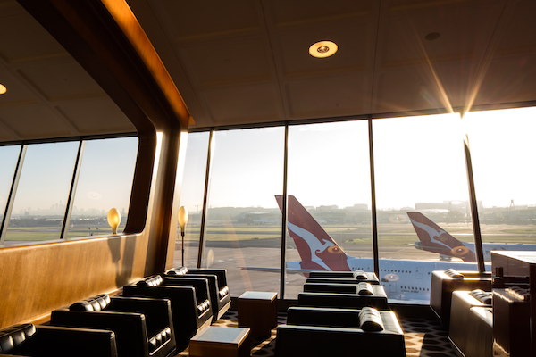 Sydney International First lounge looking out at tarmac with dual rear wing of qantas aircraft on the side during sunset